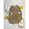 flat lay of animal print dress with yellow bag and camera