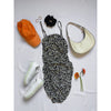 flat lay of black and white dress, orange cap, white shoes