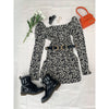 flatlay of black and white square neck dress, orange bag and black boots