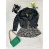 flatlay of black and white square neck dress, black leather jacket, green bag, black shoes and flowers