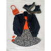 flat lay of black and white skirt, orange top, denim jacket and orange bag