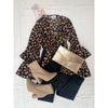 flat lay of animal print top, black trousers and gold purse